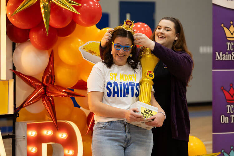 Teacher receiving recognition with a trophy and a crown